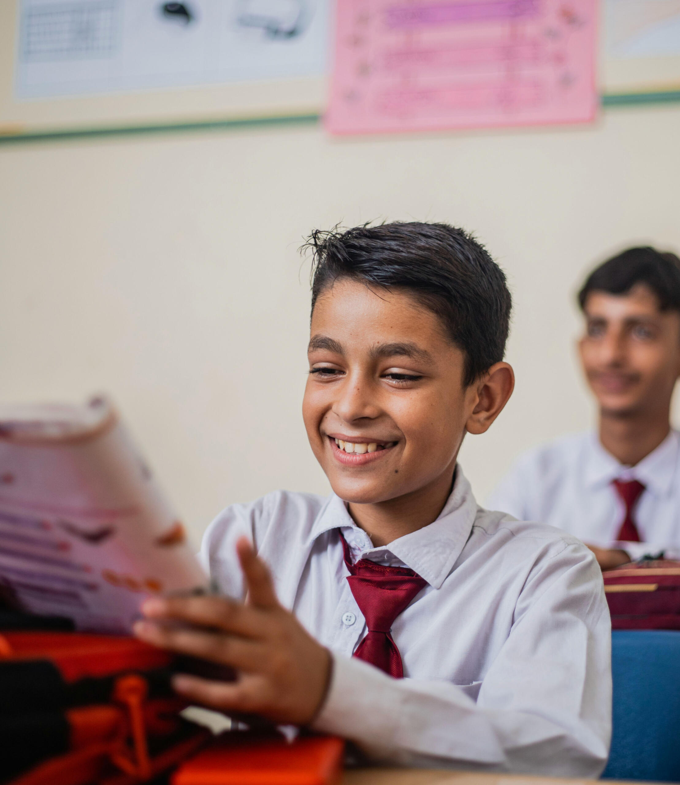 A student is holding up a program workbook, smiling