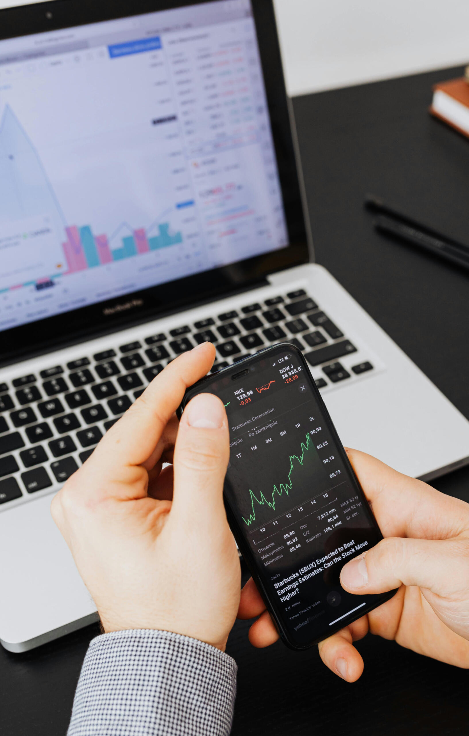 Financial Literary 101 photo A school student is holding their phone displaying stock prices and comparing this to a spreadsheet on their computer